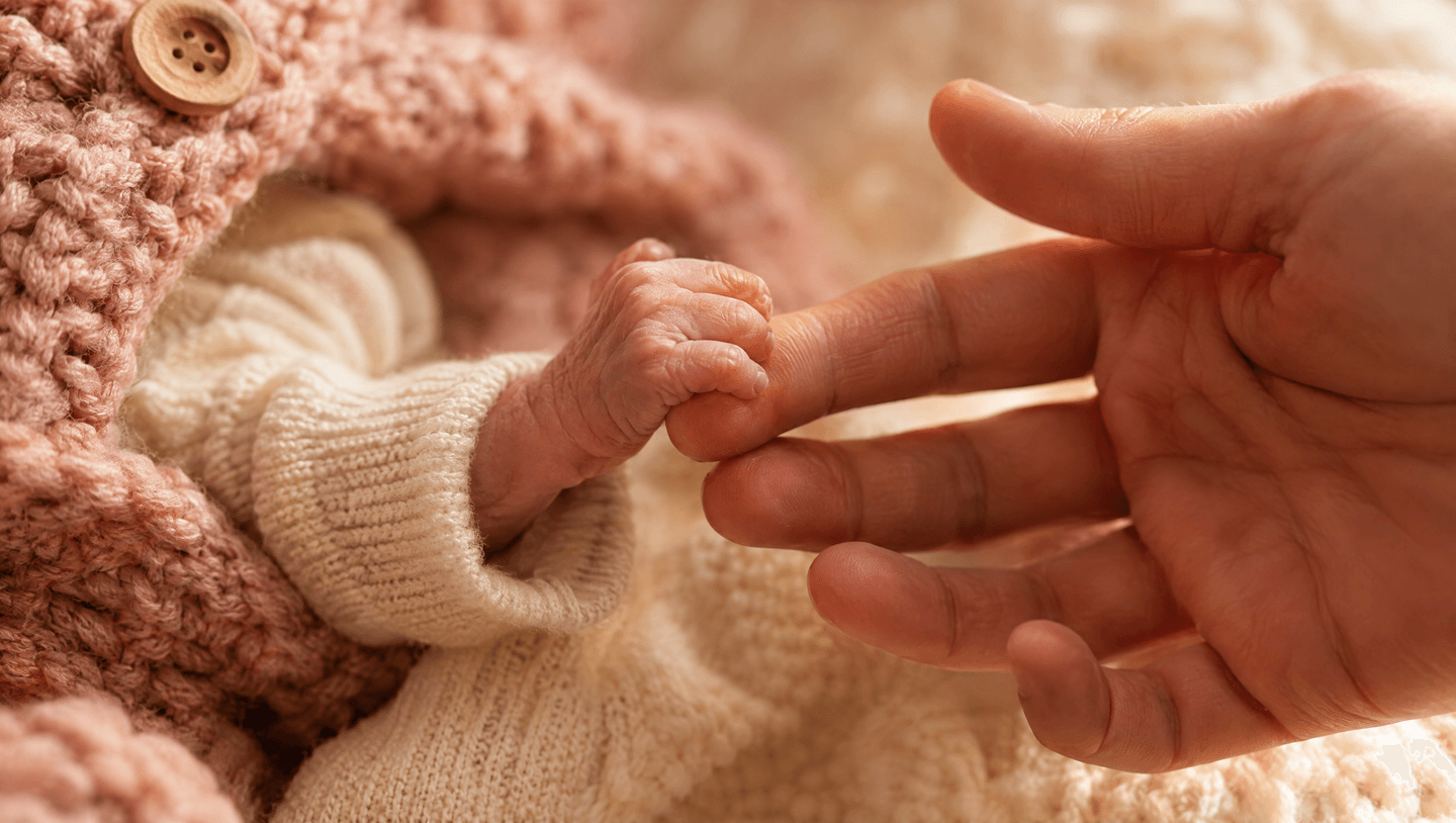 Het handje van een premature baby dat de vinger van een ouder vasthoudt